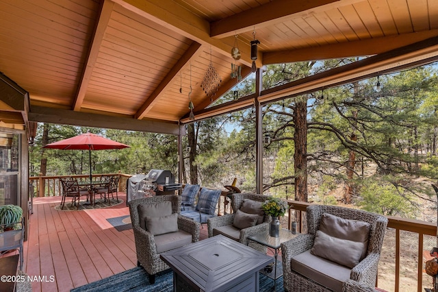 wooden deck with outdoor dining space, an outdoor living space, grilling area, and view of scattered trees