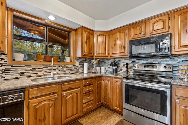kitchen with black microwave, stainless steel range with electric stovetop, a sink, tasteful backsplash, and brown cabinetry