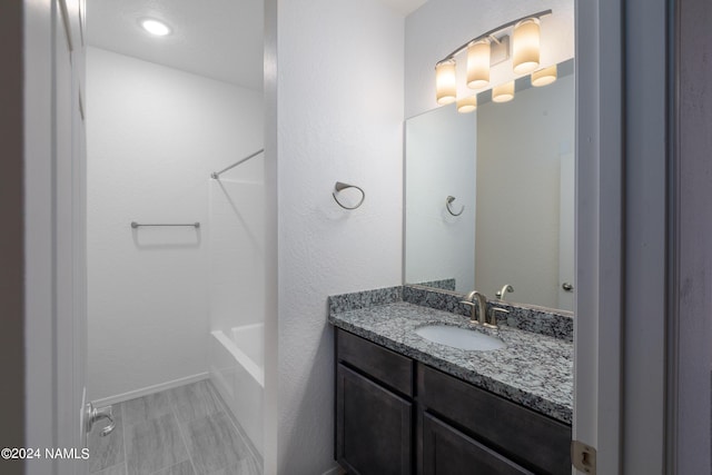 full bath with shower / bath combination, vanity, and baseboards