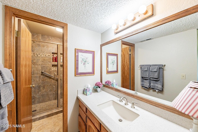 bathroom featuring vanity, an enclosed shower, and a textured ceiling