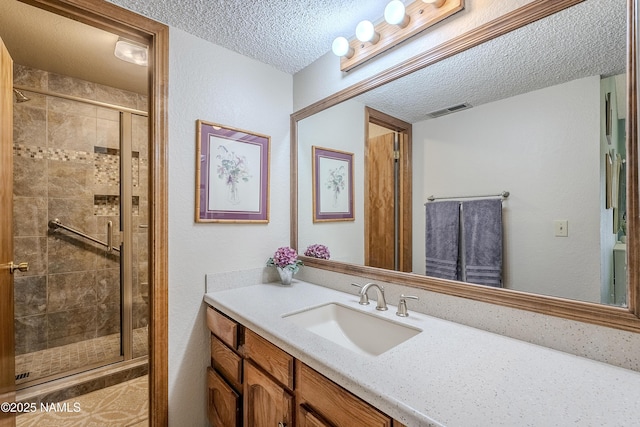 bathroom with vanity, an enclosed shower, and a textured ceiling