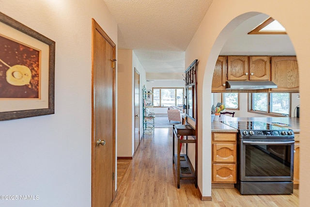 kitchen with electric stove, light hardwood / wood-style floors, and a textured ceiling