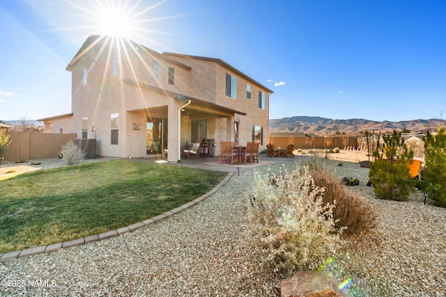 back of house with a mountain view, a patio area, and a lawn