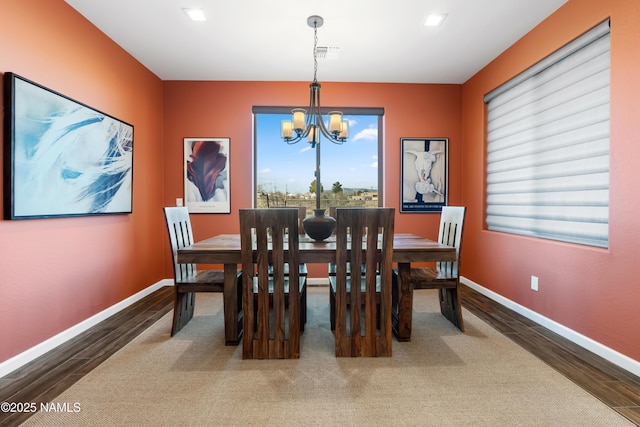 dining area featuring wood-type flooring and an inviting chandelier