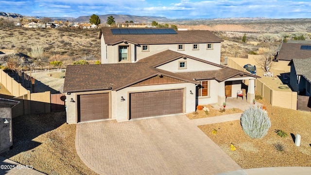 view of front of house with a garage, a mountain view, and solar panels