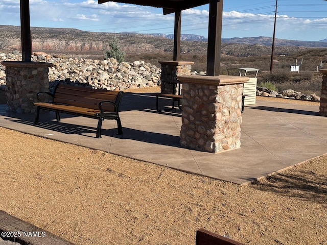 surrounding community with a bar, a mountain view, and a patio