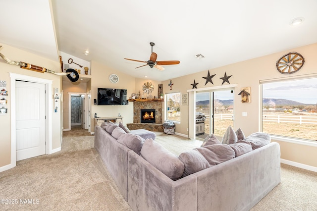 11265 N Zady Ln, Flagstaff, AZ 86004 - living room featuring light carpet, a ceiling fan, vaulted ceiling, baseboards, and a warm lit fireplace