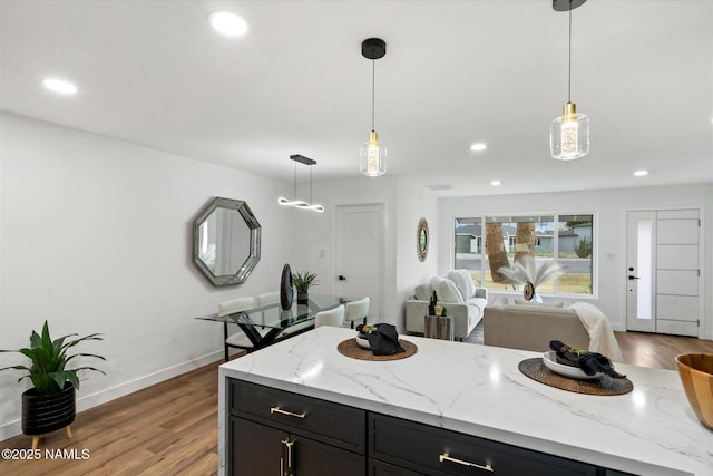 3707 E Amelia Ave, Phoenix, AZ 85018 - kitchen featuring wood finished floors, recessed lighting, pendant lighting, dark cabinetry, and light stone counters