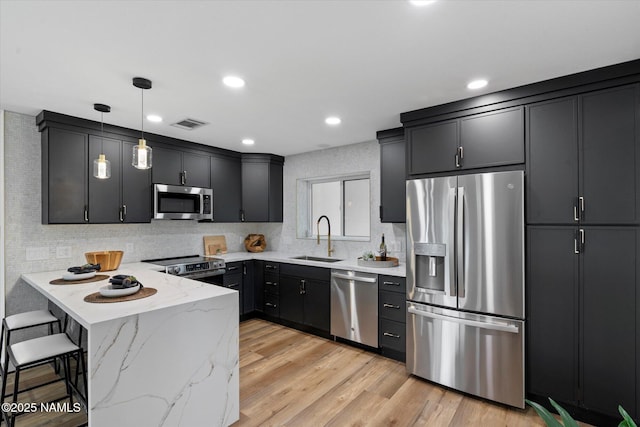 3707 E Amelia Ave, Phoenix, AZ 85018 - kitchen with stainless steel appliances, a peninsula, light stone counters, decorative light fixtures, and a kitchen bar