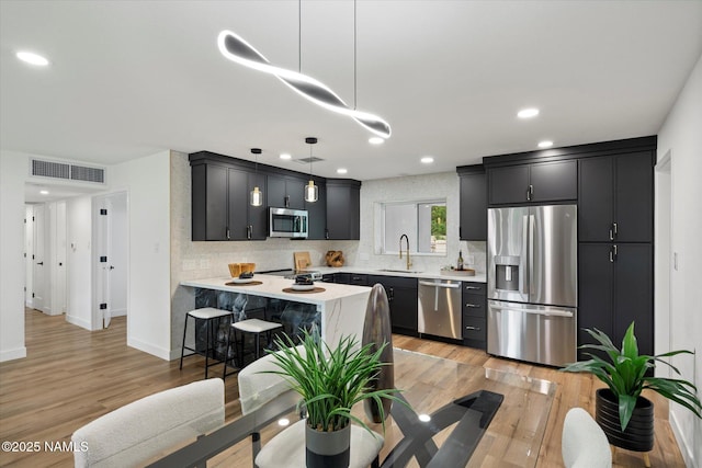 3707 E Amelia Ave, Phoenix, AZ 85018 - kitchen featuring stainless steel appliances, light countertops, dark cabinetry, a peninsula, and tasteful backsplash