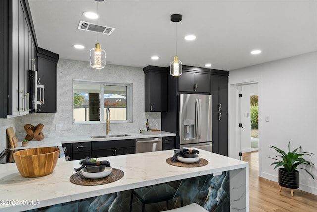3707 E Amelia Ave, Phoenix, AZ 85018 - kitchen featuring stainless steel appliances, dark cabinetry, decorative backsplash, light stone counters, and recessed lighting