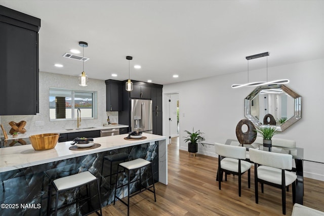 3707 E Amelia Ave, Phoenix, AZ 85018 - kitchen featuring appliances with stainless steel finishes, dark cabinets, a breakfast bar, a peninsula, and dark wood-style flooring