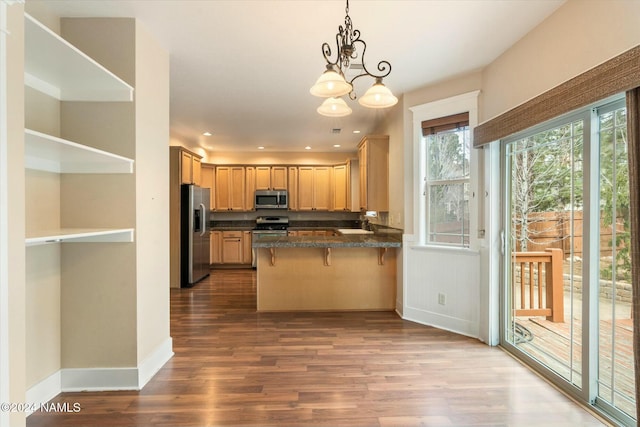 kitchen with pendant lighting, a breakfast bar area, kitchen peninsula, stainless steel appliances, and light hardwood / wood-style flooring