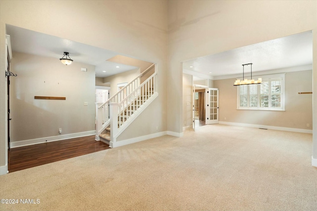 carpeted empty room featuring an inviting chandelier and ornamental molding