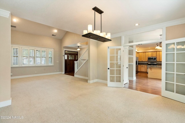 interior space featuring french doors, lofted ceiling, ornamental molding, and light carpet