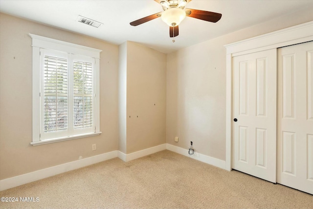 unfurnished bedroom featuring light colored carpet, a closet, and ceiling fan