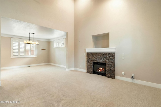 unfurnished living room with ornamental molding, carpet floors, a chandelier, and a fireplace