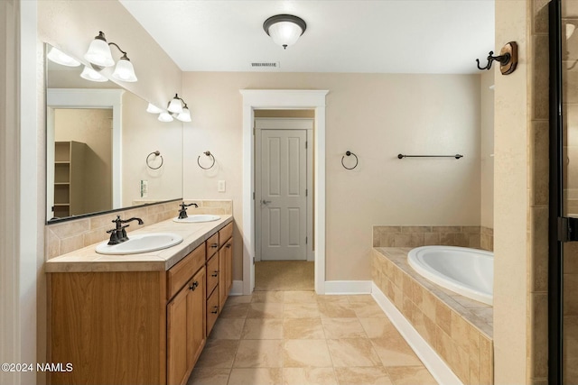 bathroom featuring tasteful backsplash, vanity, and tiled bath