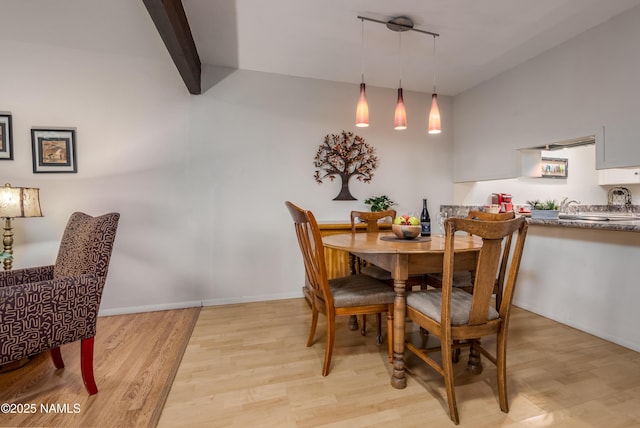 dining area with light wood-type flooring, beam ceiling, and baseboards