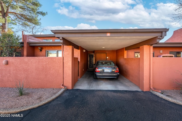 view of car parking with a carport, fence, and driveway