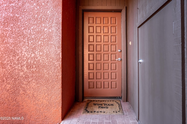 doorway to property featuring stucco siding