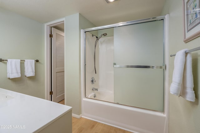 full bathroom with enclosed tub / shower combo, a textured ceiling, wood finished floors, and vanity