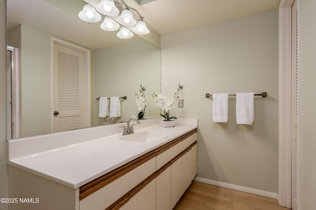 bathroom with wood finished floors, vanity, and baseboards