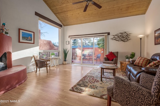 living room with a fireplace with raised hearth, wood ceiling, ceiling fan, vaulted ceiling, and wood finished floors