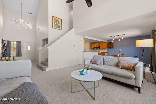 living room with ceiling fan, light colored carpet, a towering ceiling, and track lighting