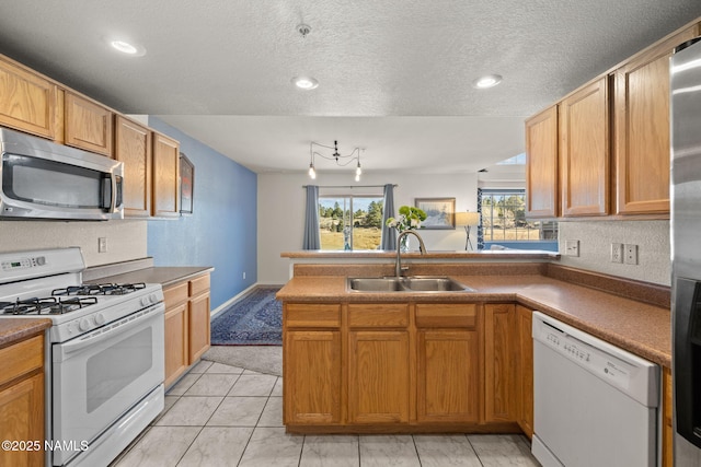 kitchen featuring sink, white appliances, kitchen peninsula, and a textured ceiling