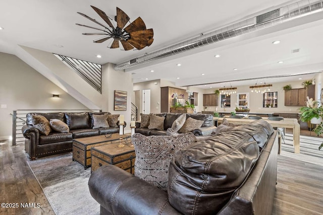 living area with recessed lighting, visible vents, stairway, an inviting chandelier, and wood finished floors