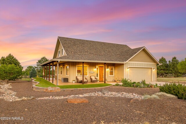 10833 Sage Rd, Flagstaff, AZ 86004 - view of front facade featuring board and batten siding, roof with shingles, a patio area, a garage, and concrete driveway