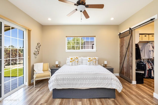 10833 Sage Rd, Flagstaff, AZ 86004 - bedroom featuring access to outside, baseboards, a walk in closet, a barn door, and wood finished floors