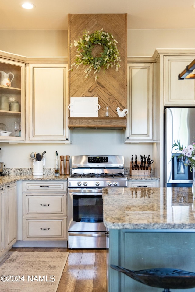 10833 Sage Rd, Flagstaff, AZ 86004 - kitchen featuring glass insert cabinets, cream cabinets, light stone countertops, appliances with stainless steel finishes, and light wood finished floors