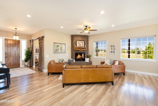 10833 Sage Rd, Flagstaff, AZ 86004 - living room featuring a barn door, light wood-type flooring, a ceiling fan, a fireplace, and recessed lighting