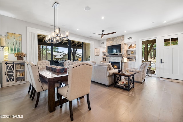 dining room with a wealth of natural light, built in shelves, a stone fireplace, and light wood-type flooring