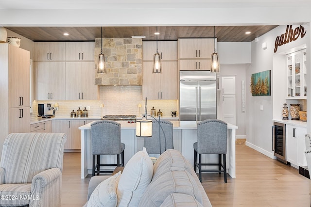 kitchen featuring built in refrigerator, hanging light fixtures, decorative backsplash, and a breakfast bar area