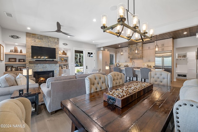 dining area featuring sink, ceiling fan, a stone fireplace, and dark hardwood / wood-style floors