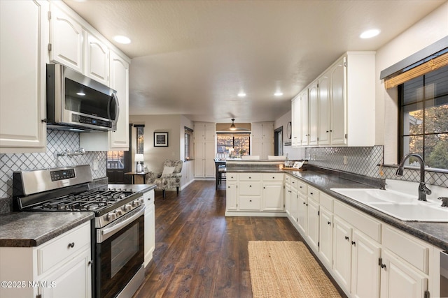 kitchen featuring sink, dark wood-type flooring, appliances with stainless steel finishes, white cabinetry, and kitchen peninsula