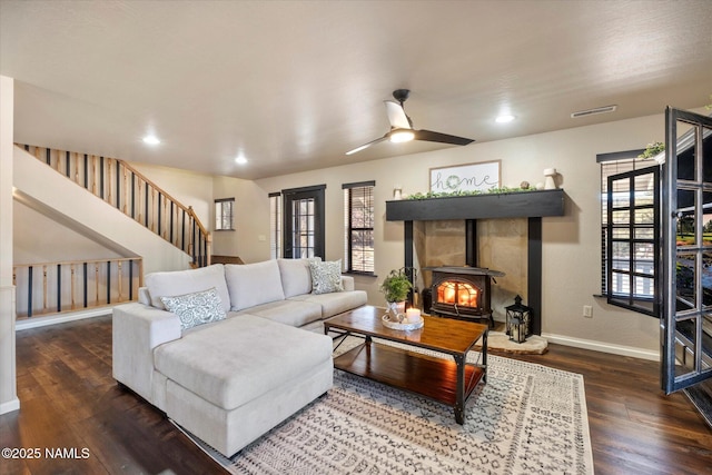 living room featuring ceiling fan, dark hardwood / wood-style floors, and a wood stove