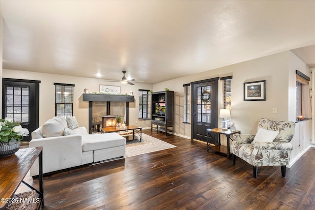 living room with ceiling fan, a wood stove, and dark hardwood / wood-style floors