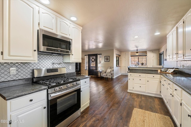 kitchen with appliances with stainless steel finishes, white cabinets, dark hardwood / wood-style flooring, and kitchen peninsula