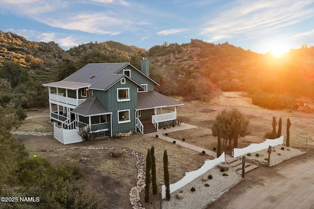 back house at dusk with a mountain view and a sunroom