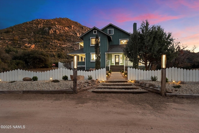 view of front of house featuring a standing seam roof, metal roof, a fenced front yard, and a mountain view