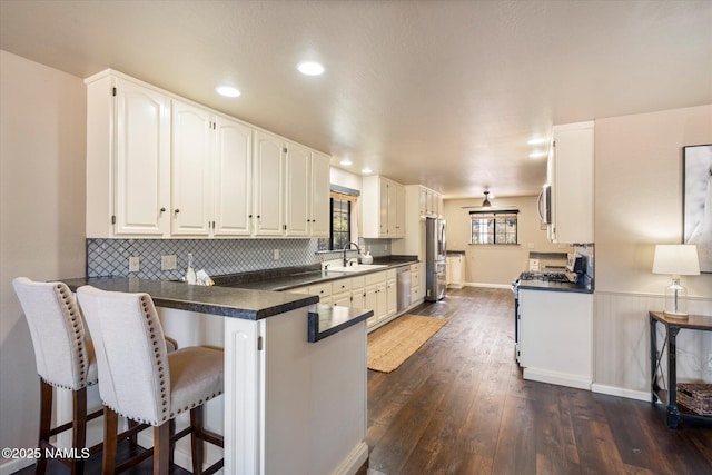 kitchen with white cabinetry, appliances with stainless steel finishes, dark wood-type flooring, and kitchen peninsula