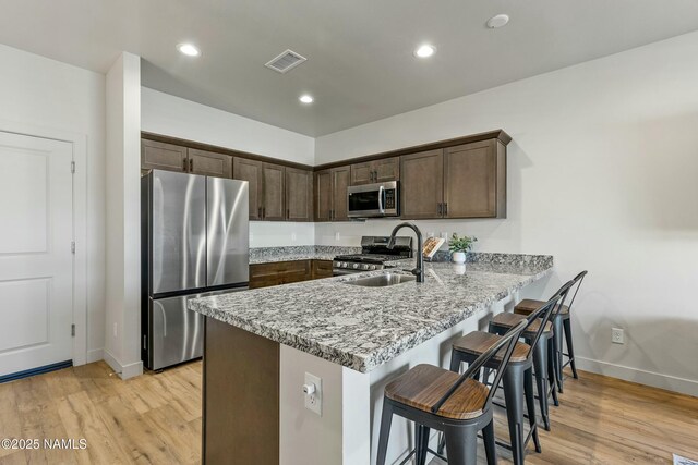 12220 Curtis Ct, Bellemont, AZ 86015 - kitchen with a peninsula, light wood-type flooring, appliances with stainless steel finishes, a sink, and baseboards