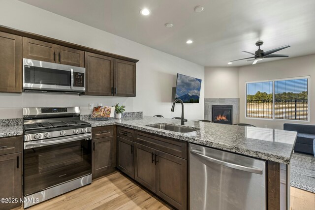 12220 Curtis Ct, Bellemont, AZ 86015 - kitchen featuring a peninsula, dark brown cabinets, a ceiling fan, appliances with stainless steel finishes, and a sink