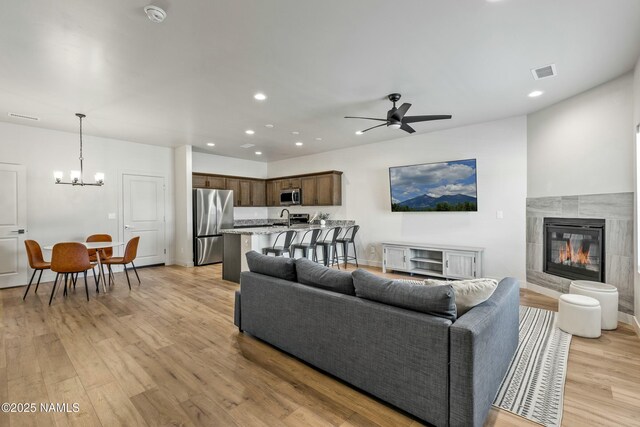 12220 Curtis Ct, Bellemont, AZ 86015 - living area featuring light wood-type flooring, a fireplace, recessed lighting, visible vents, and ceiling fan with notable chandelier