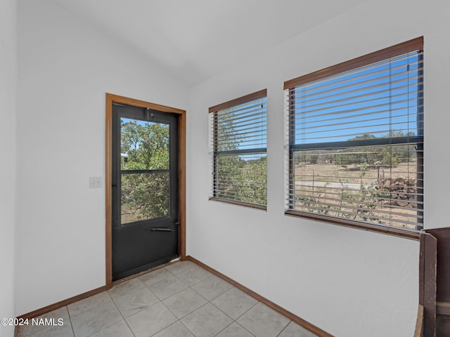 doorway with vaulted ceiling, a wealth of natural light, and light tile patterned floors