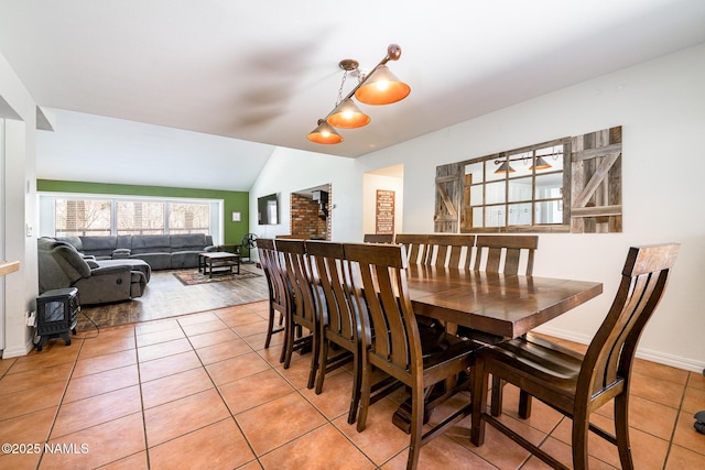 dining area featuring baseboards, light tile patterned flooring, and vaulted ceiling